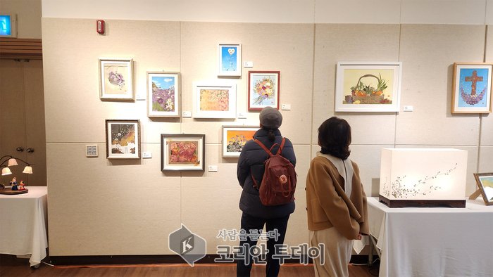 [코리안투데이] 전시 관계자가 관객에게 작품에 대해 설명하고 있다. © 변아롱 기자
