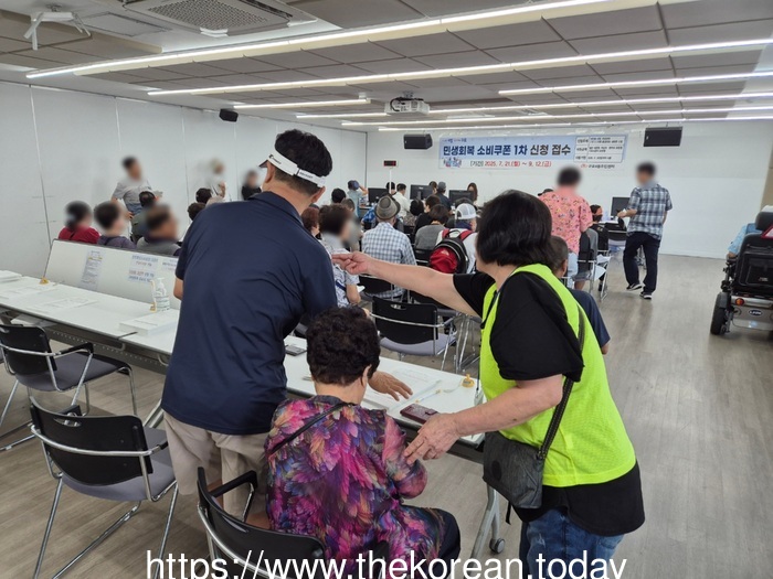 [코리안투데이] (사진) 구로4동 주민센터에서 자원봉사자가 어르신에게 민생회복 소비쿠폰 신청 방법을 안내하고 있다. © 박수진 기자