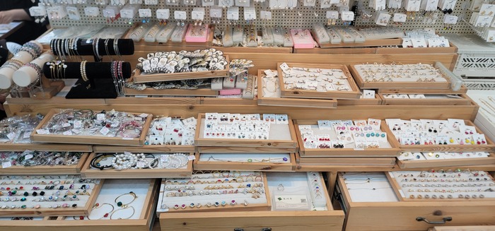 [Korean Today] Diversos acessórios de moda, incluindo brincos, colares, pérolas e peças com cristais, estão expostos na loja da JOY YOU no Mercado de 